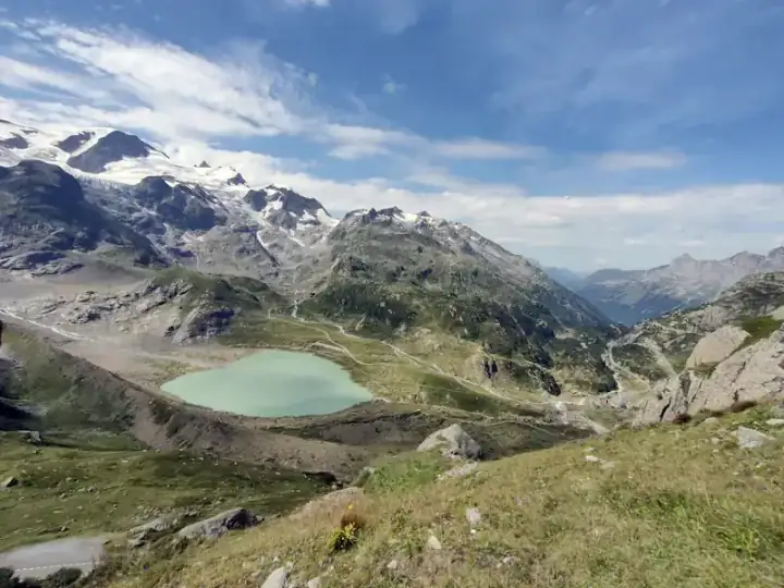 A turquoise alpine lake below snow-capped Swiss peaks