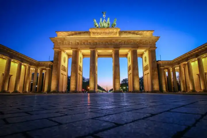 The Brandenburg Gate in Berlin, floodlit against a deep blue dusk sky