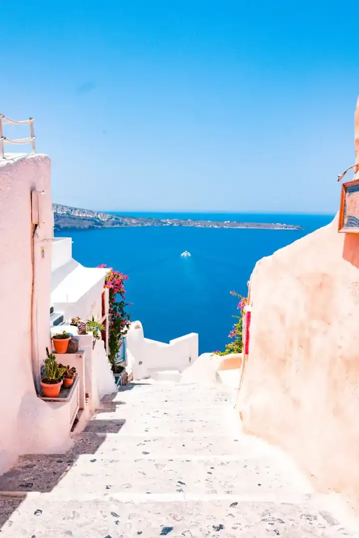 Whitewashed steps in Santorini leading down towards the blue Aegean